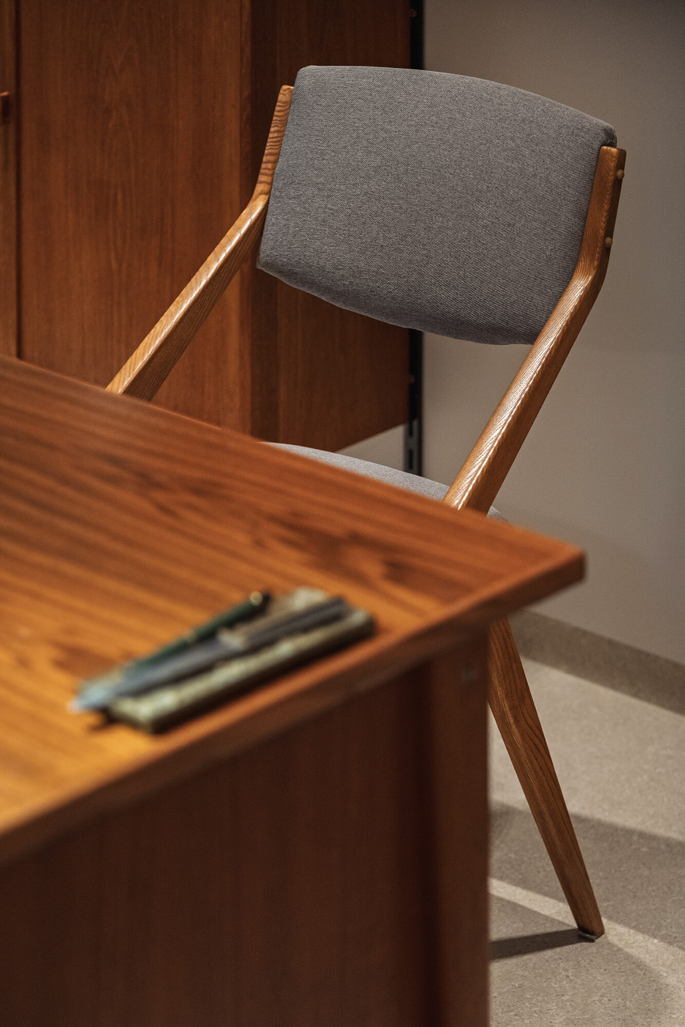 Drewniane biurko i krzesło z szarą tapicerką. Minimalistyczny design.