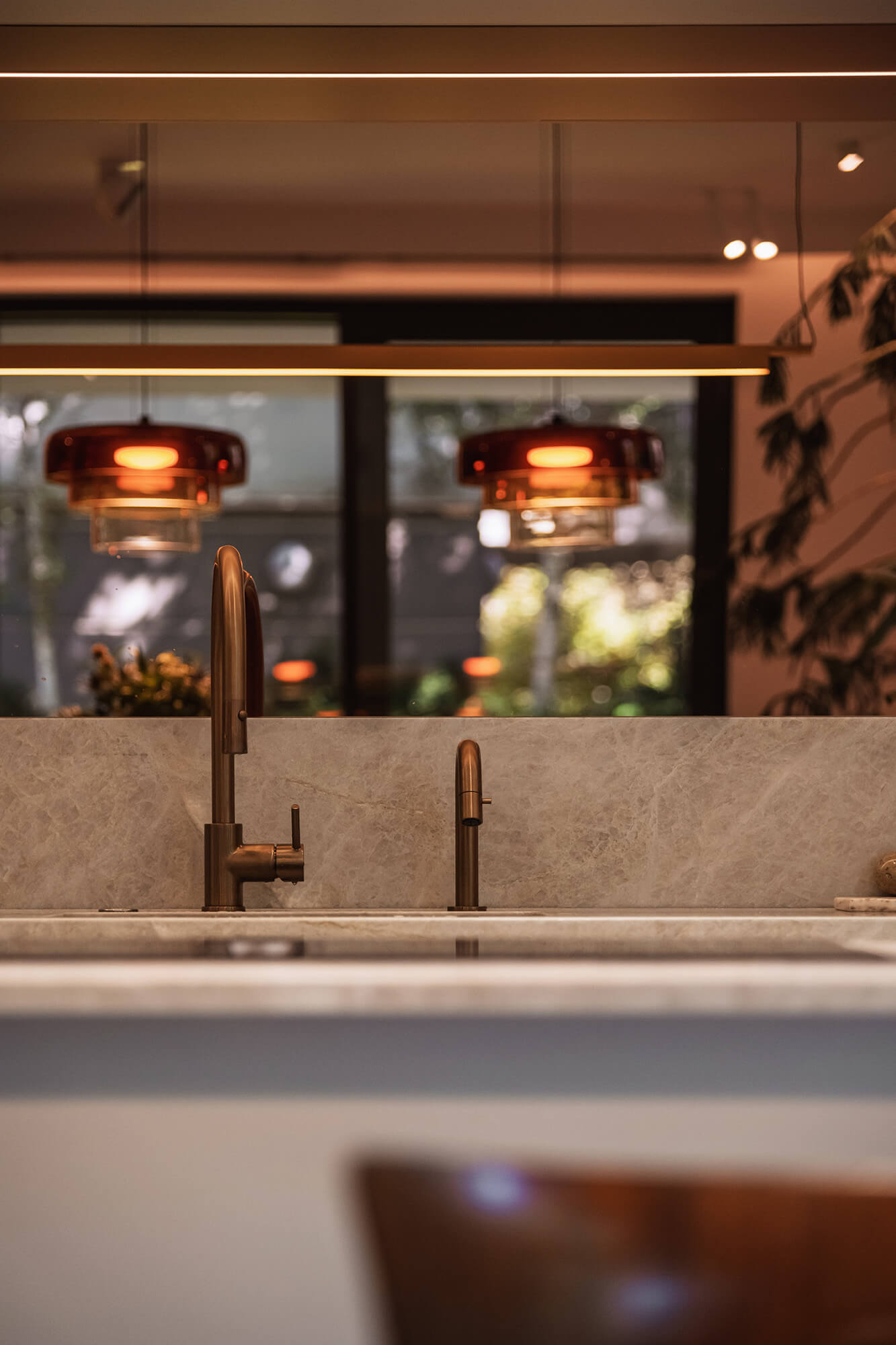 Nowoczesna kuchnia z marmurowym blatem, złotą baterią i lampami. Eleganckie wnętrze.