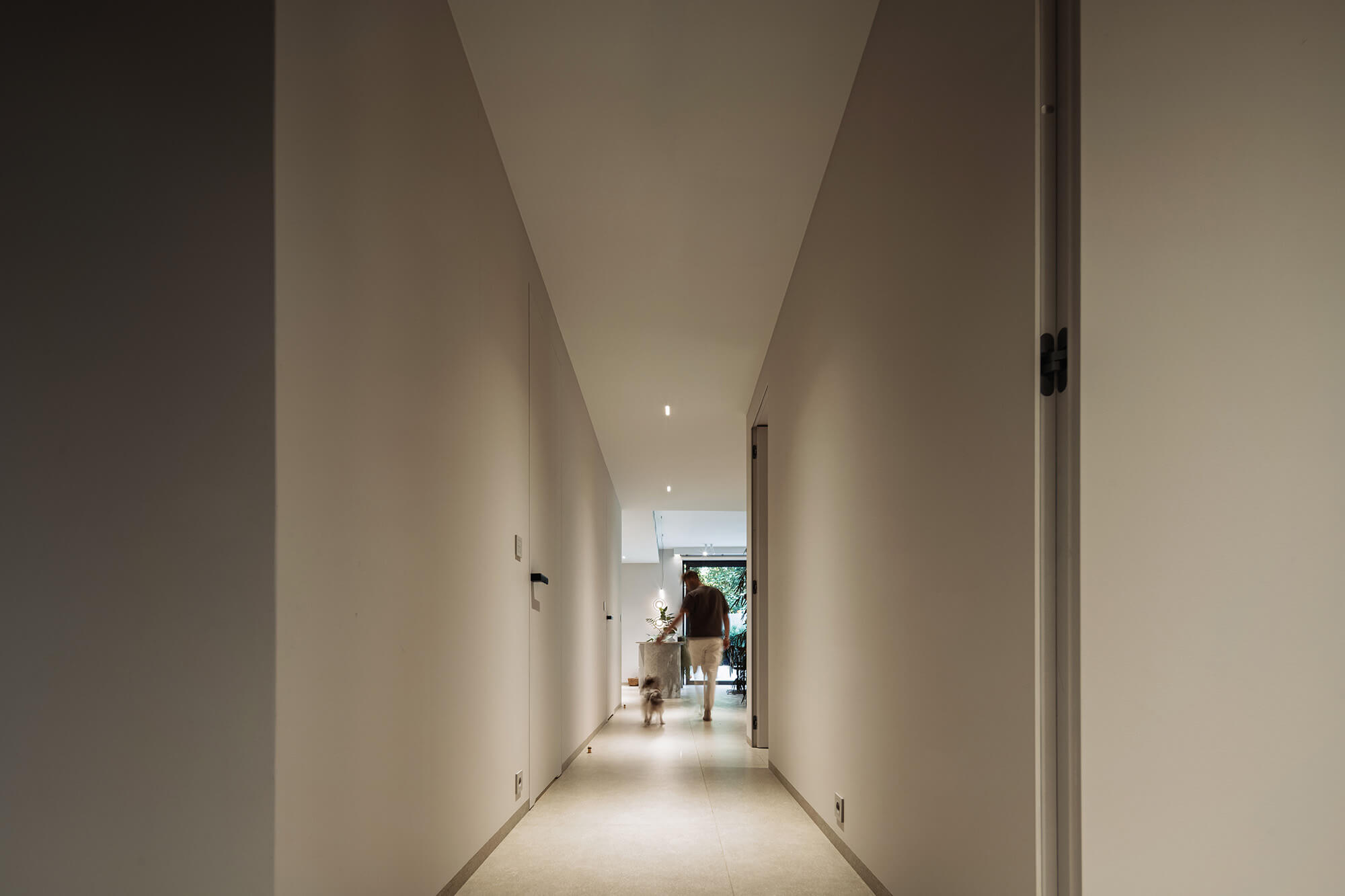 Osoba wyprowadzająca psa na nowoczesny, minimalistyczny korytarz