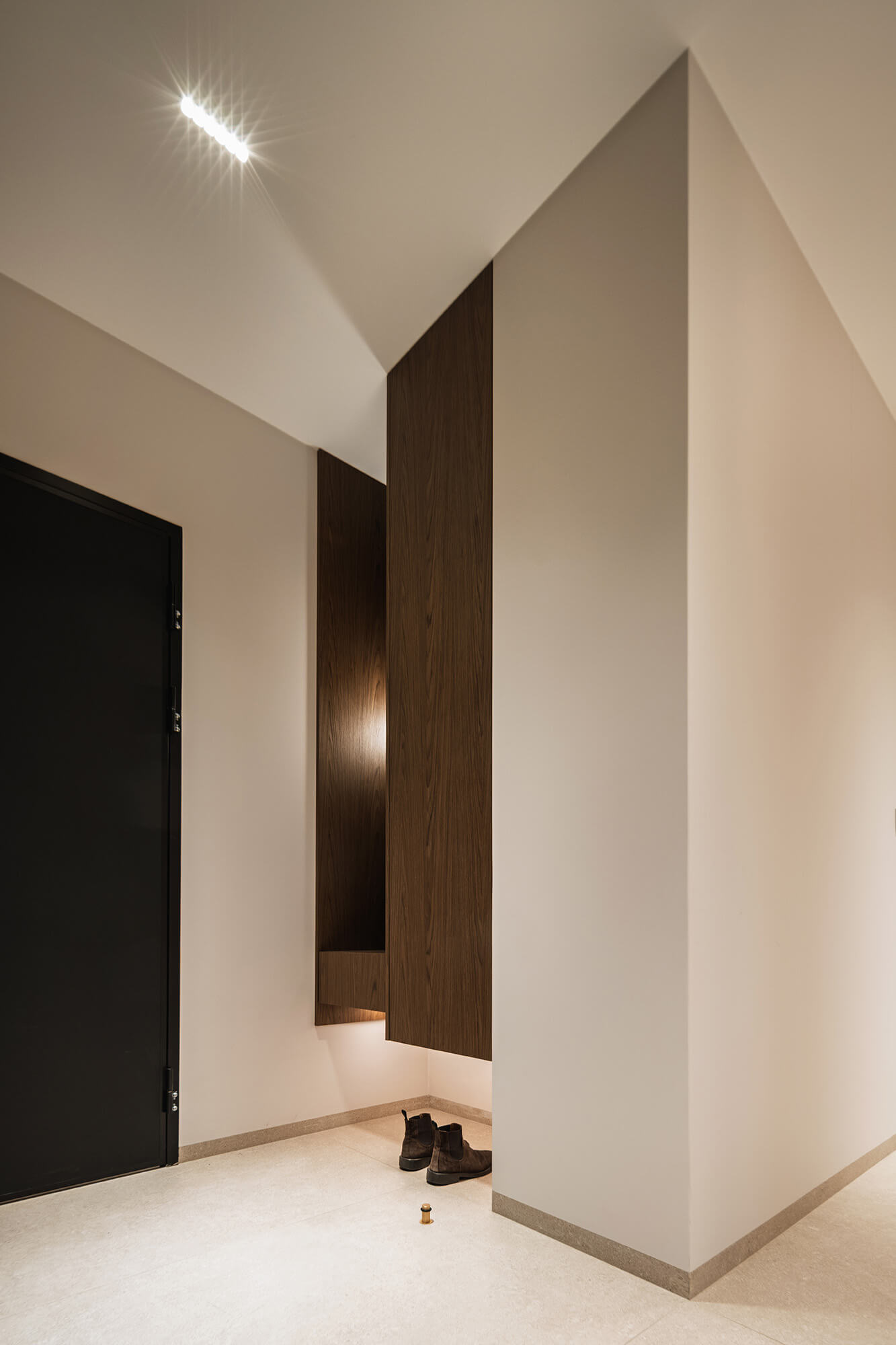 Nowoczesny przedpokój z drewnianą zabudową i butami. Minimalistyczny design.