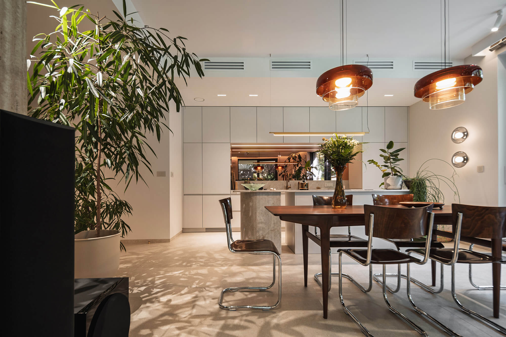 Nowoczesna kuchnia z drewnianym stołem, roślinami doniczkowymi i lampami wiszącymi