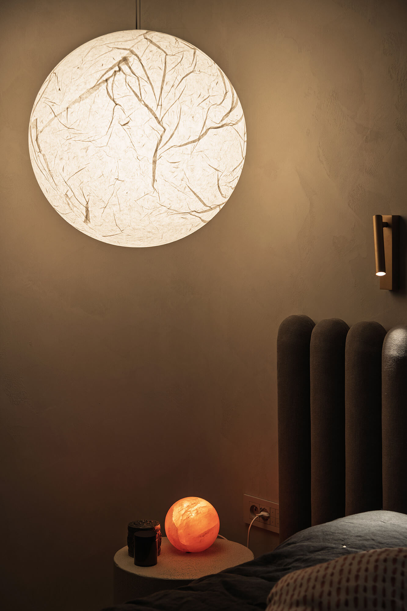 Klimatyczna sypialnia z lampą księżycową, lampką nocną i wezgłowiem łóżka. Przytulne oświetlenie.