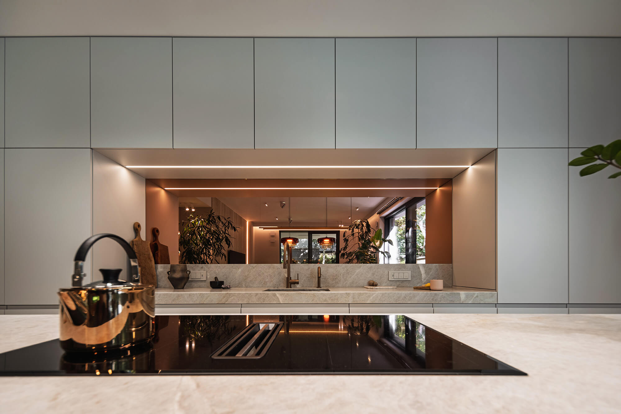 Nowoczesna kuchnia z płytą indukcyjną, złotym czajnikiem i szarymi szafkami. Minimalistyczny design kuchni.