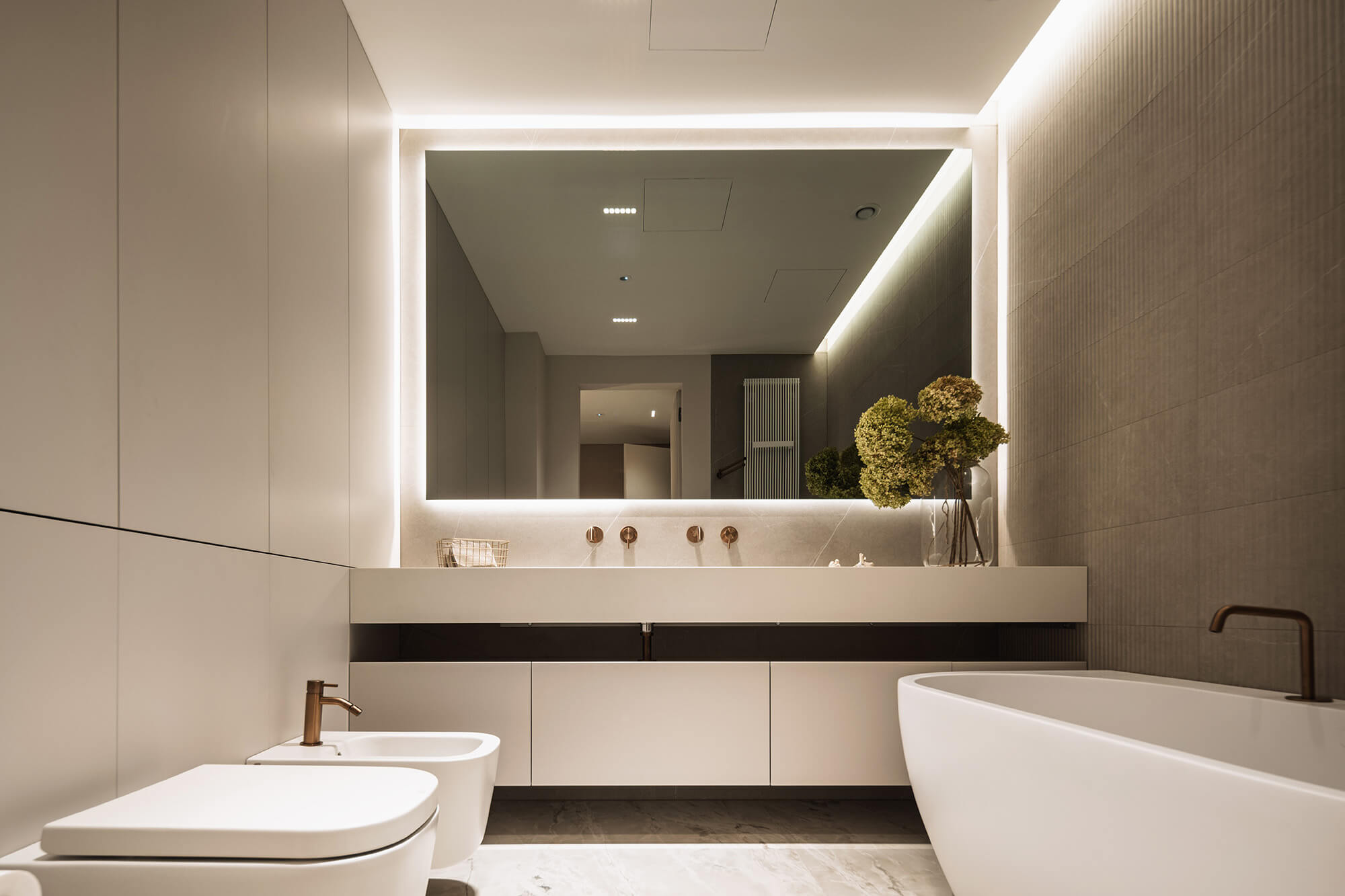 Modern minimalist bathroom with a large mirror, white vanity, and freestanding tub.