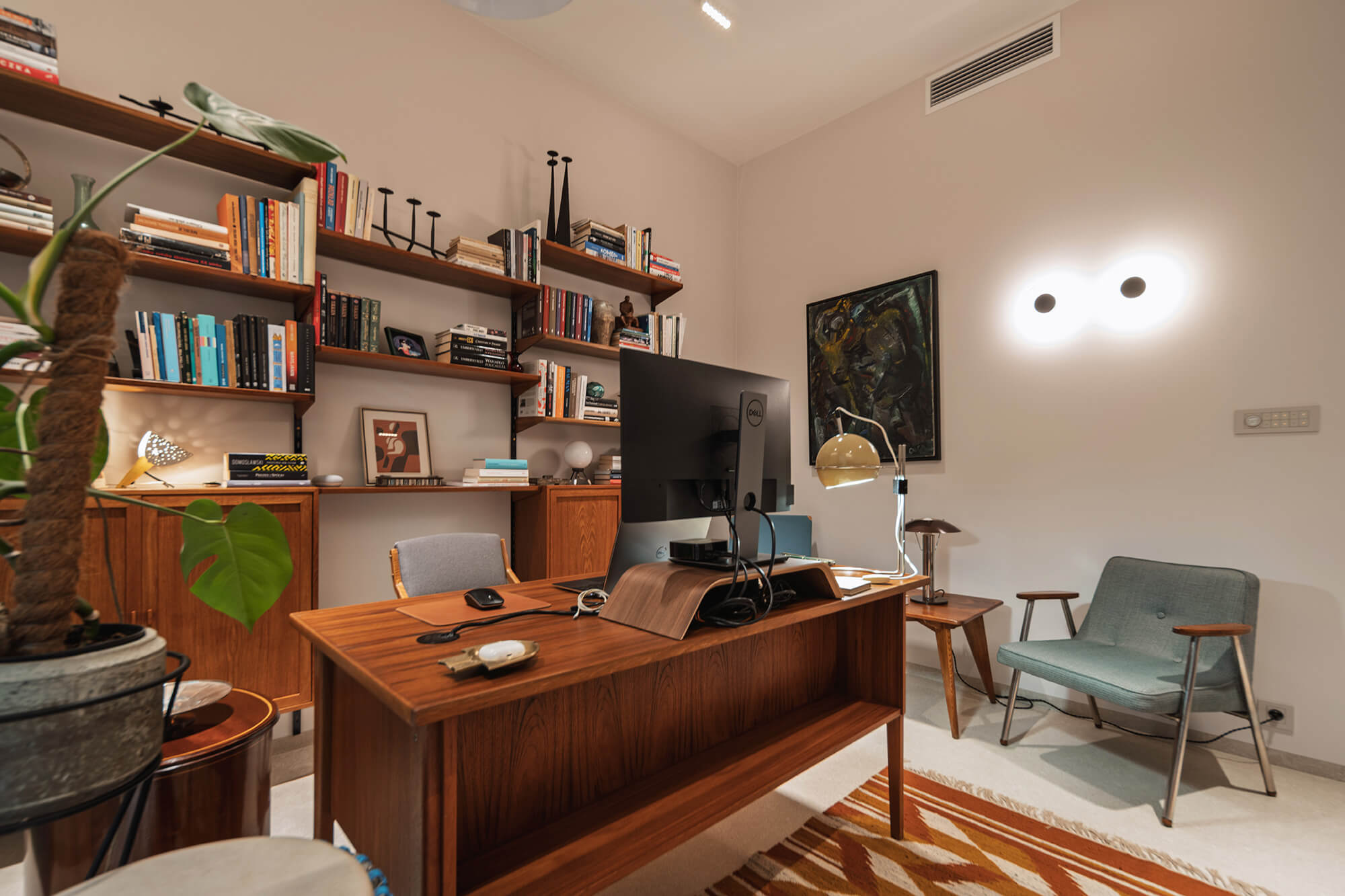 Stylowe domowe biuro z drewnianym biurkiem, regałami i zielonym fotelem. Przytulne wnętrze do pracy.
