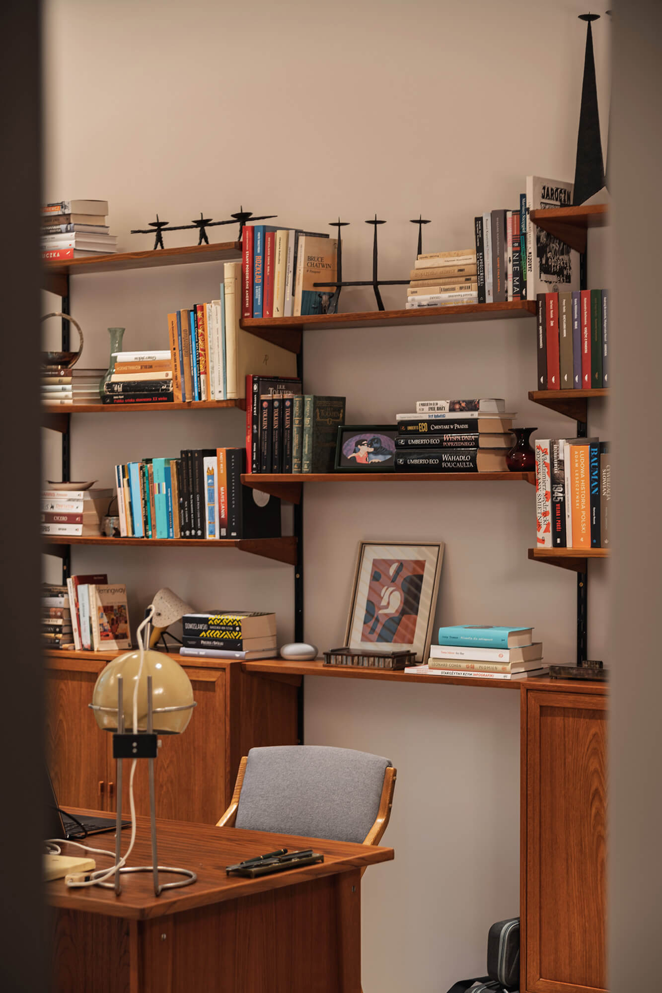 Półka z książkami, biurko z lampą i krzesłem. Domowe biuro w stylu vintage.