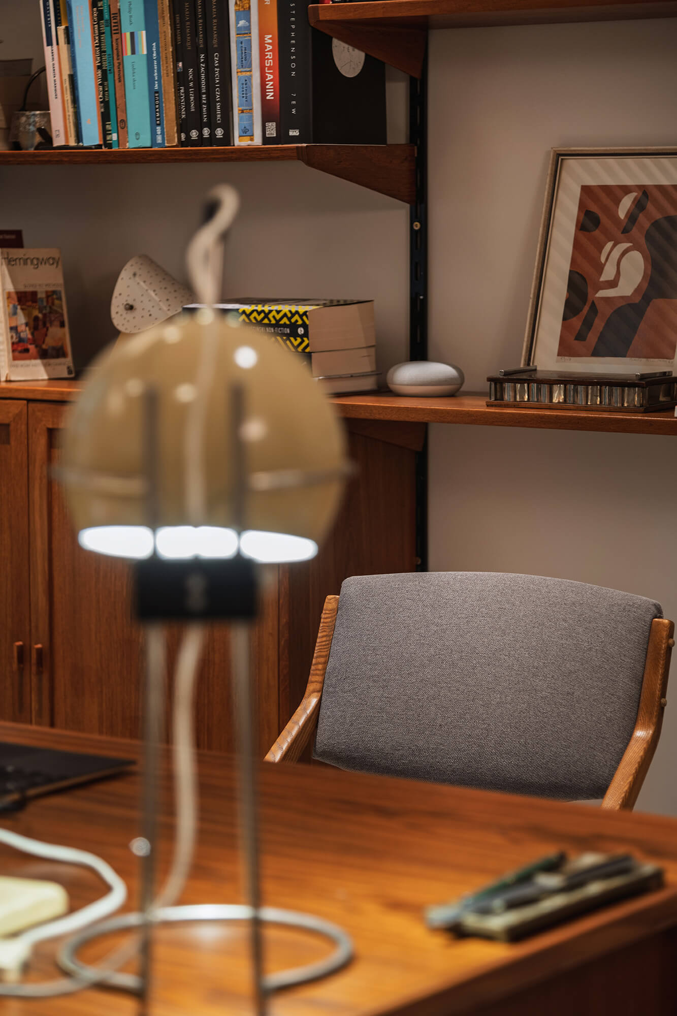 Biurko z lampką i krzesłem na tle półek z książkami. Przytulne miejsce do pracy w domu.