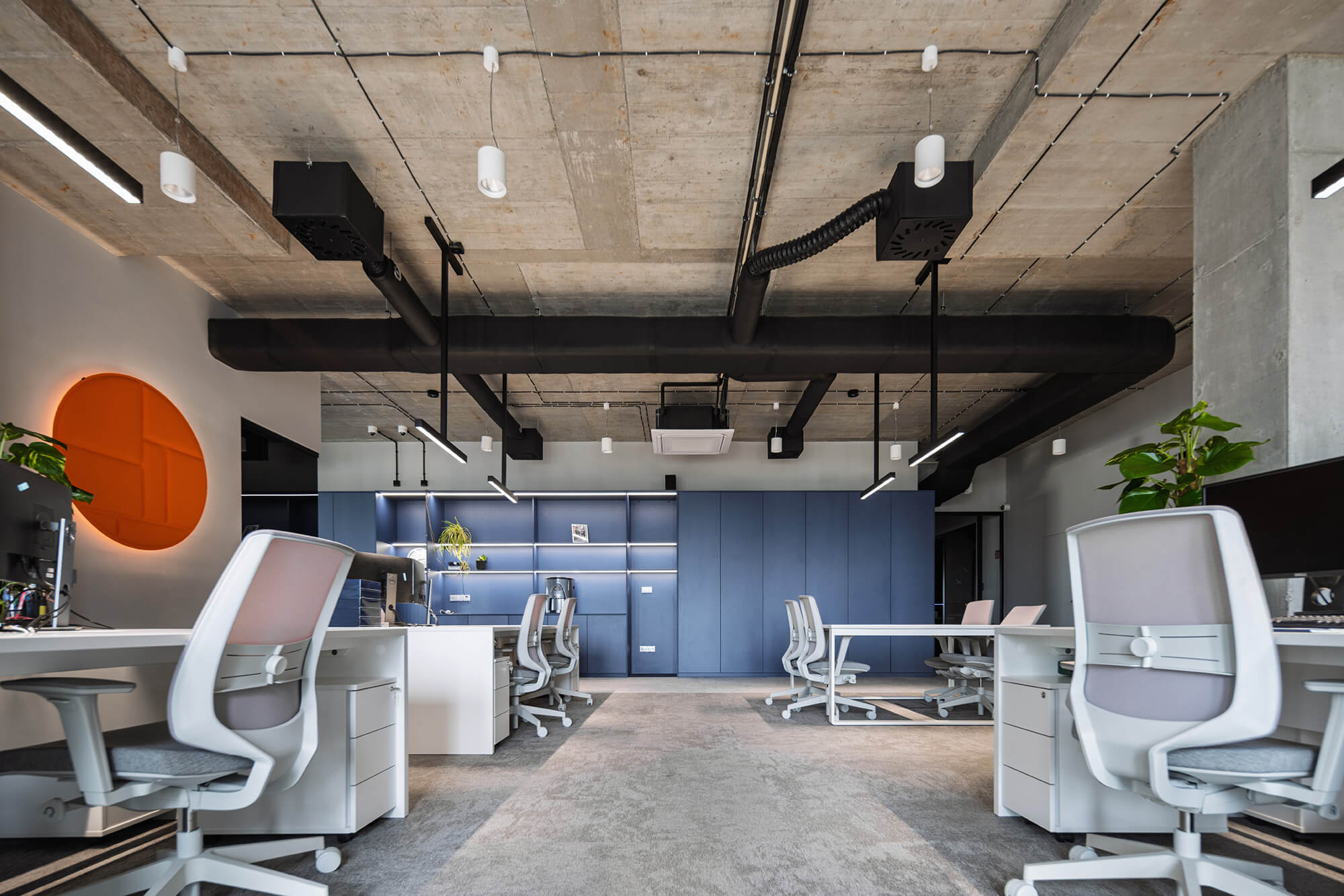 Nowoczesne biuro z szarymi krzesłami i betonowym sufitem.