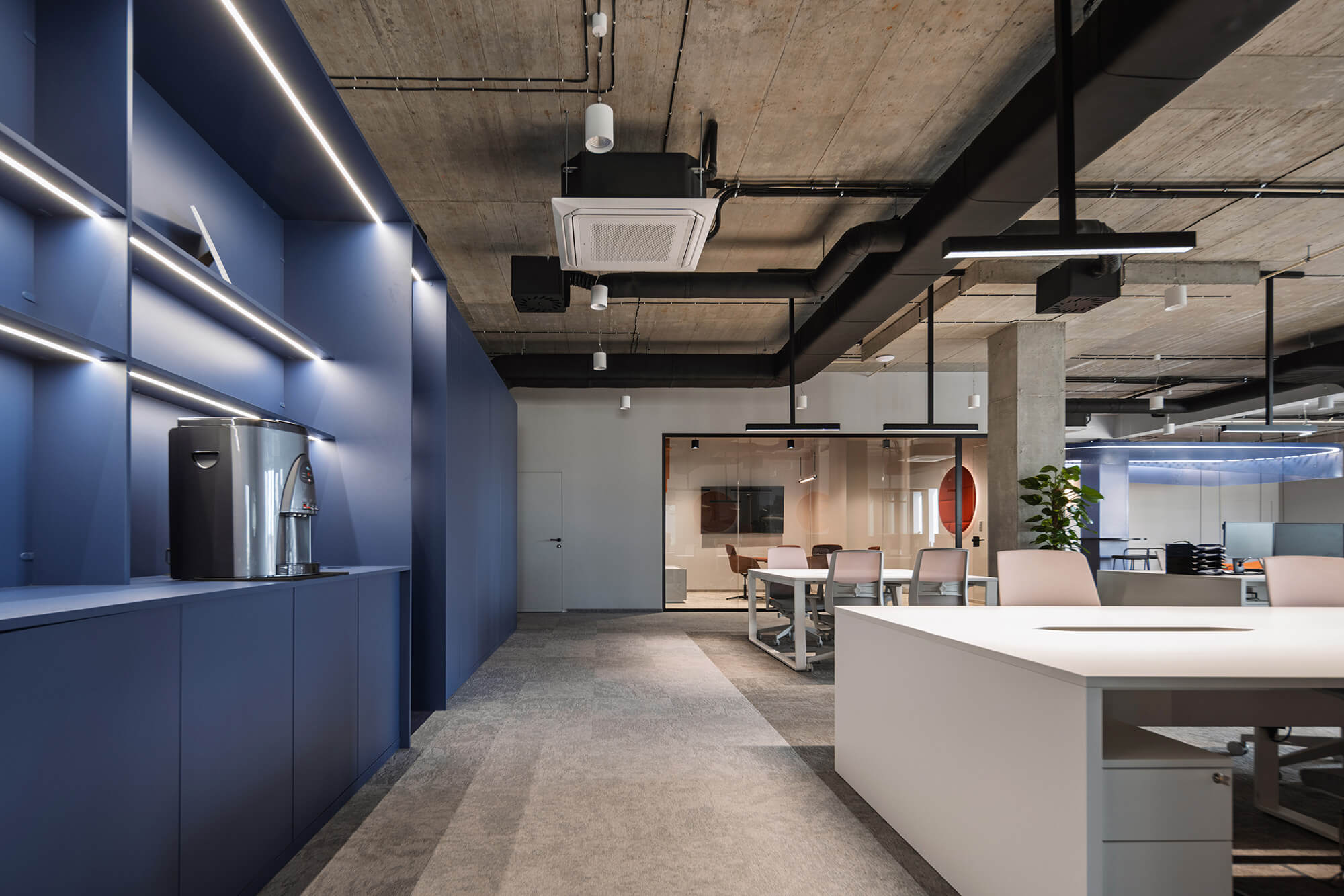 Nowoczesne biuro z niebieską zabudową, betonowym sufitem i otwartą przestrzenią do pracy. Projekt /008k overis.