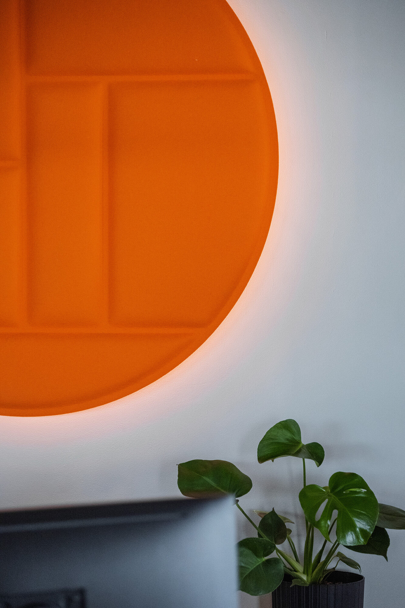 Pomarańczowy okrągły panel ścienny z doniczkową rośliną w pobliżu