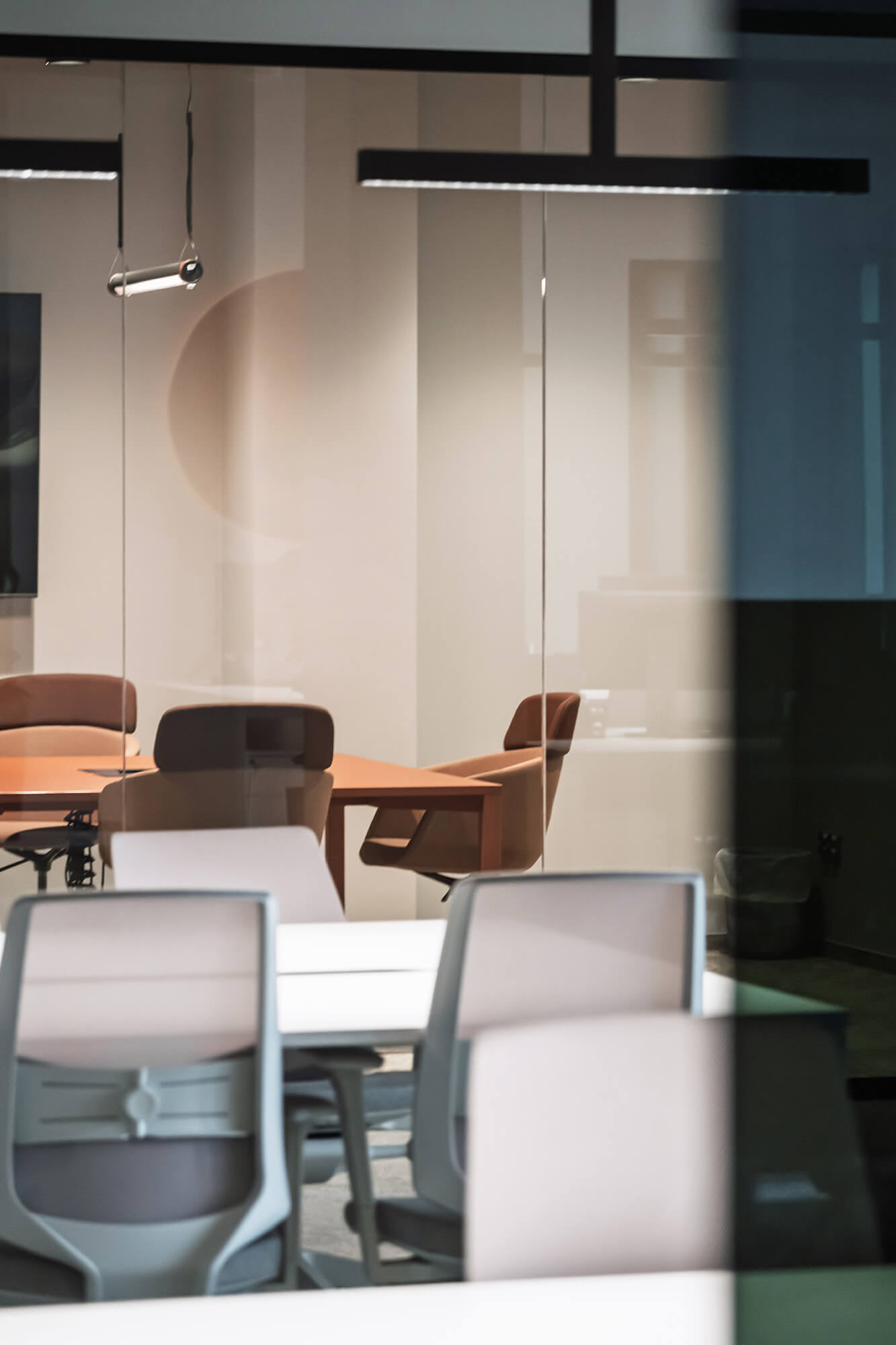 Sala konferencyjna z brązowymi krzesłami i szklanymi ścianami.