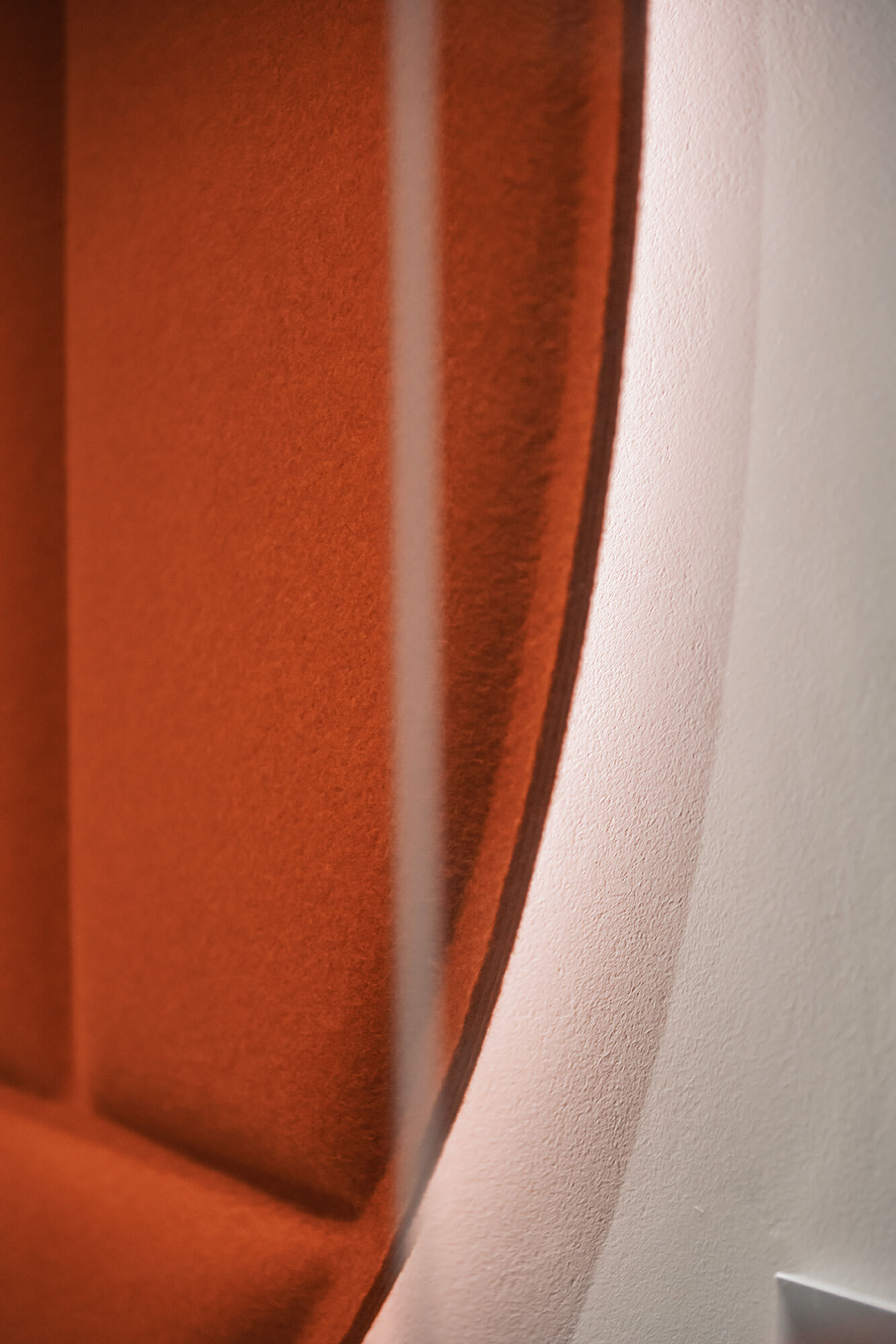 Pomarańczowy panel akustyczny na białej ścianie. Detal wnętrza z /008k overis.