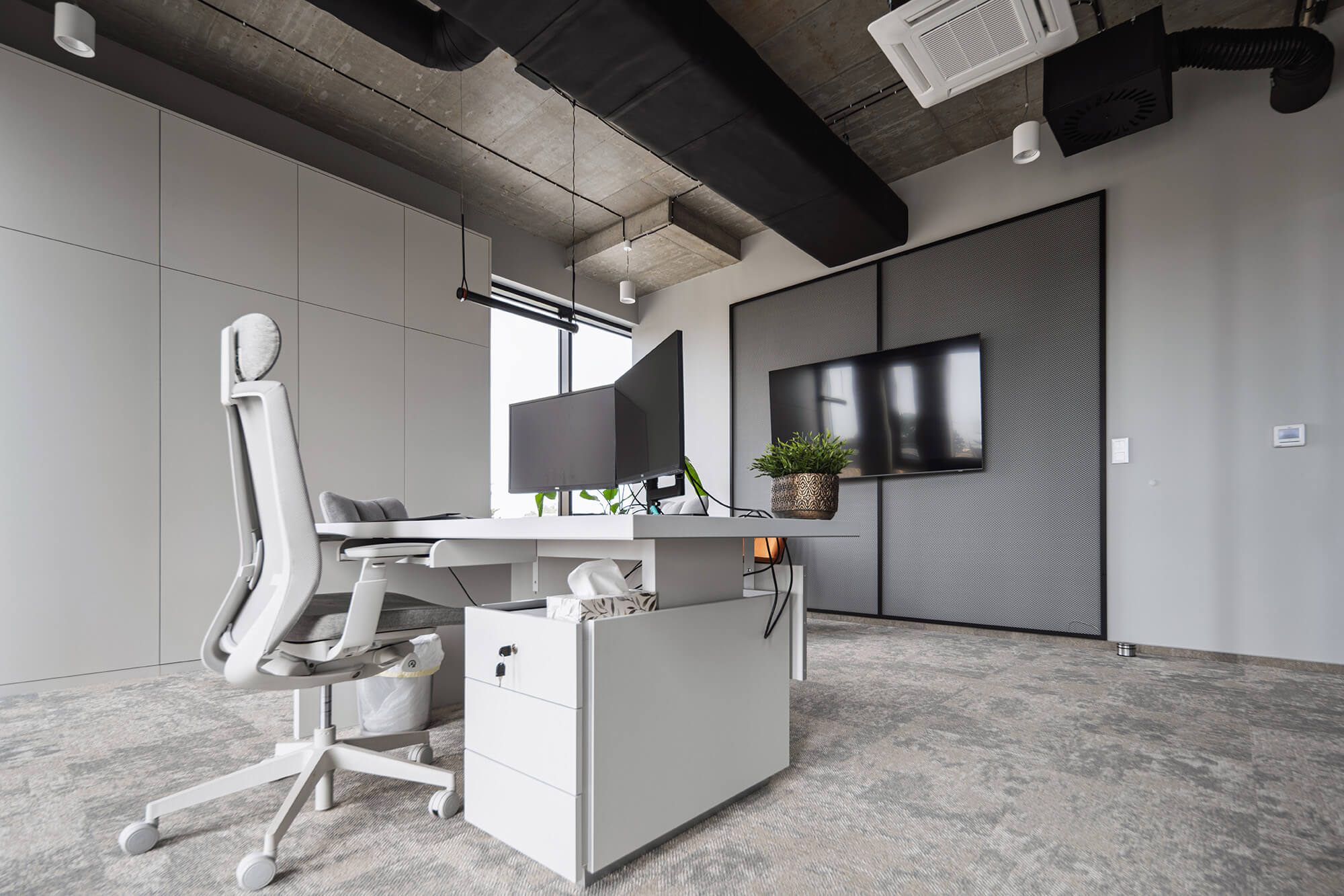Nowoczesne biuro z białym biurkiem, krzesłem i szarą ścianą. Minimalistyczny design.