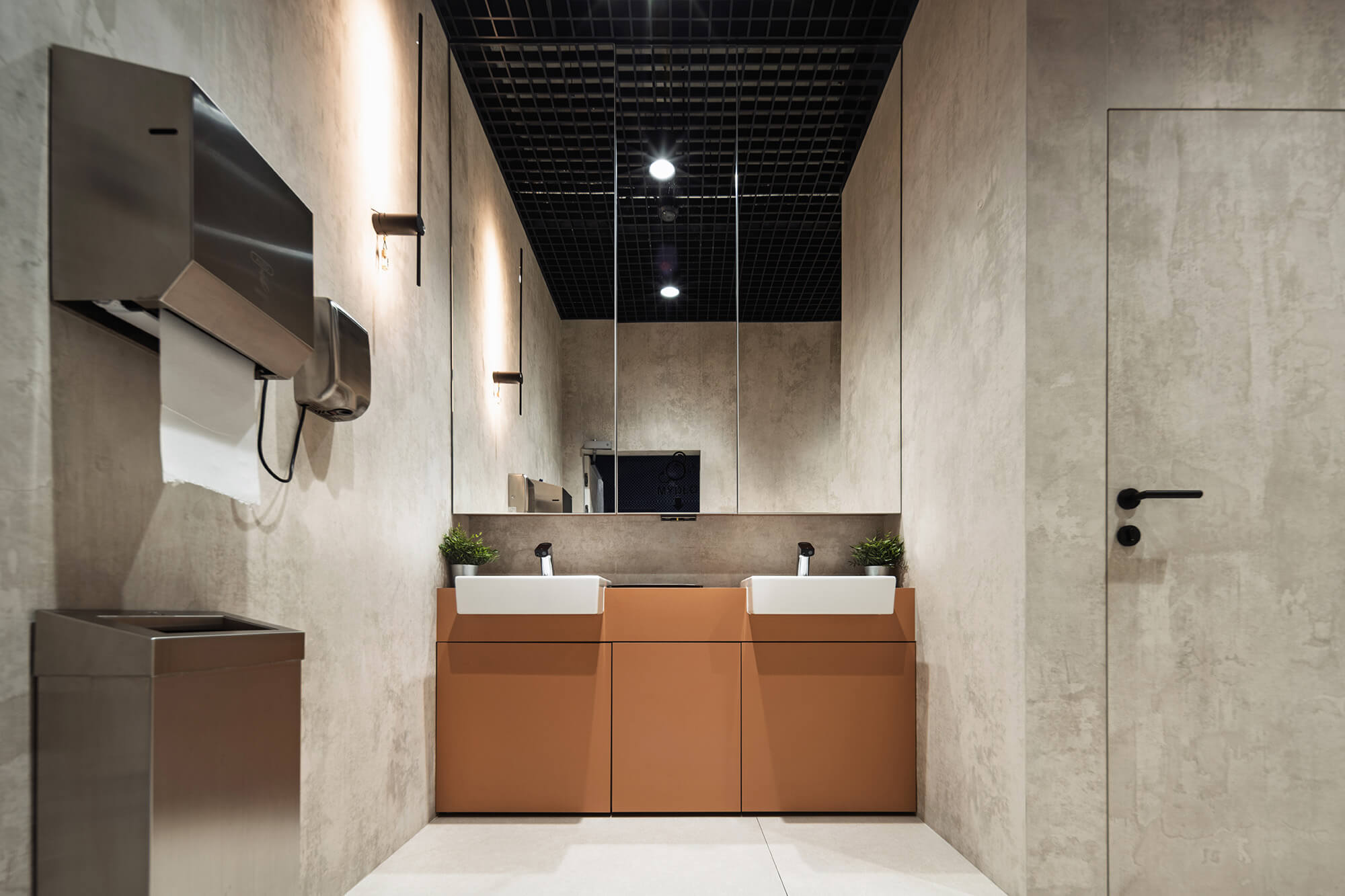 Nowoczesna łazienka z umywalkami, lustrem i dozownikiem ręczników. Minimalistyczny design.