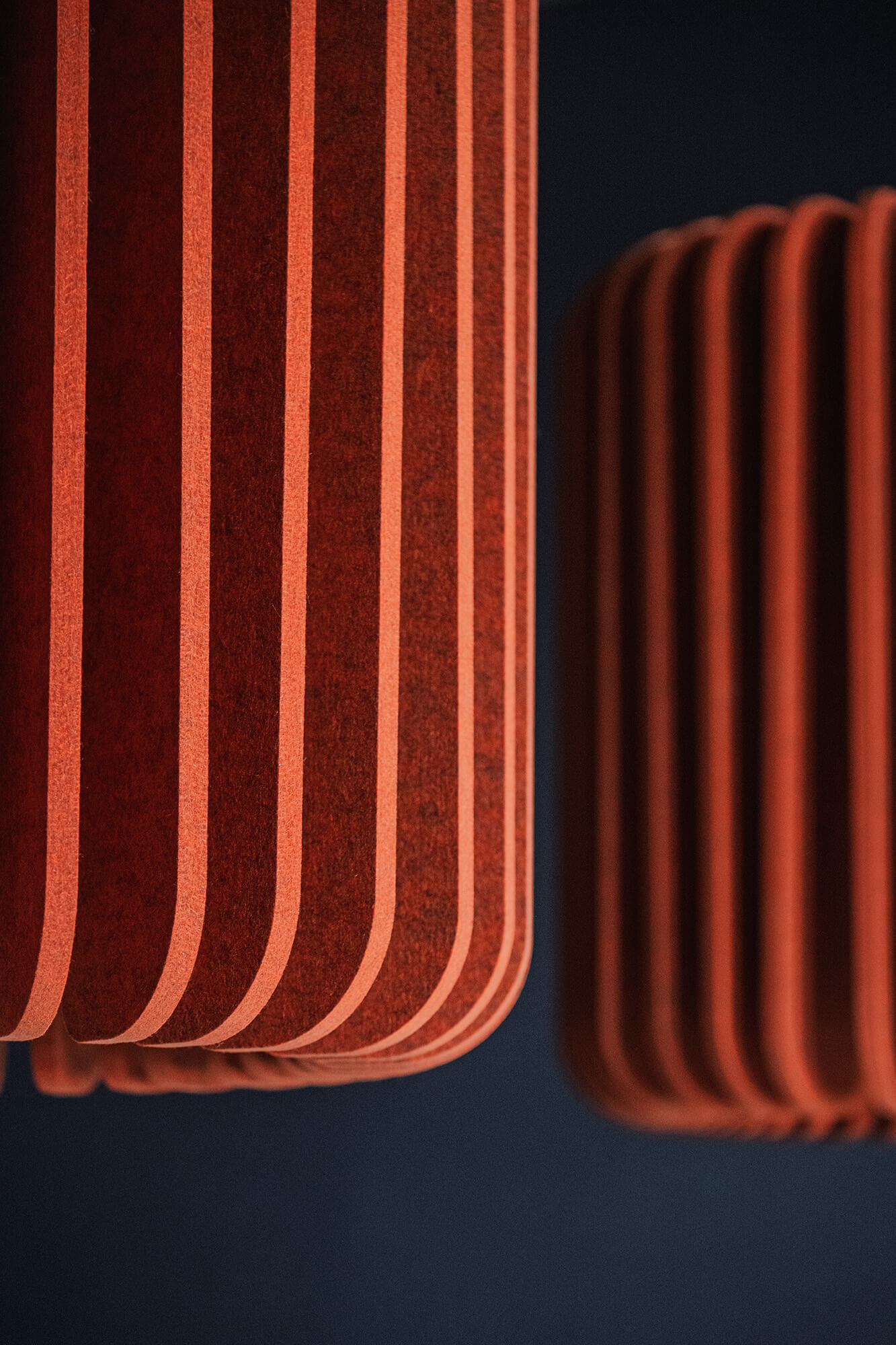 Pomarańczowe panele akustyczne z filcu na ciemnym tle.