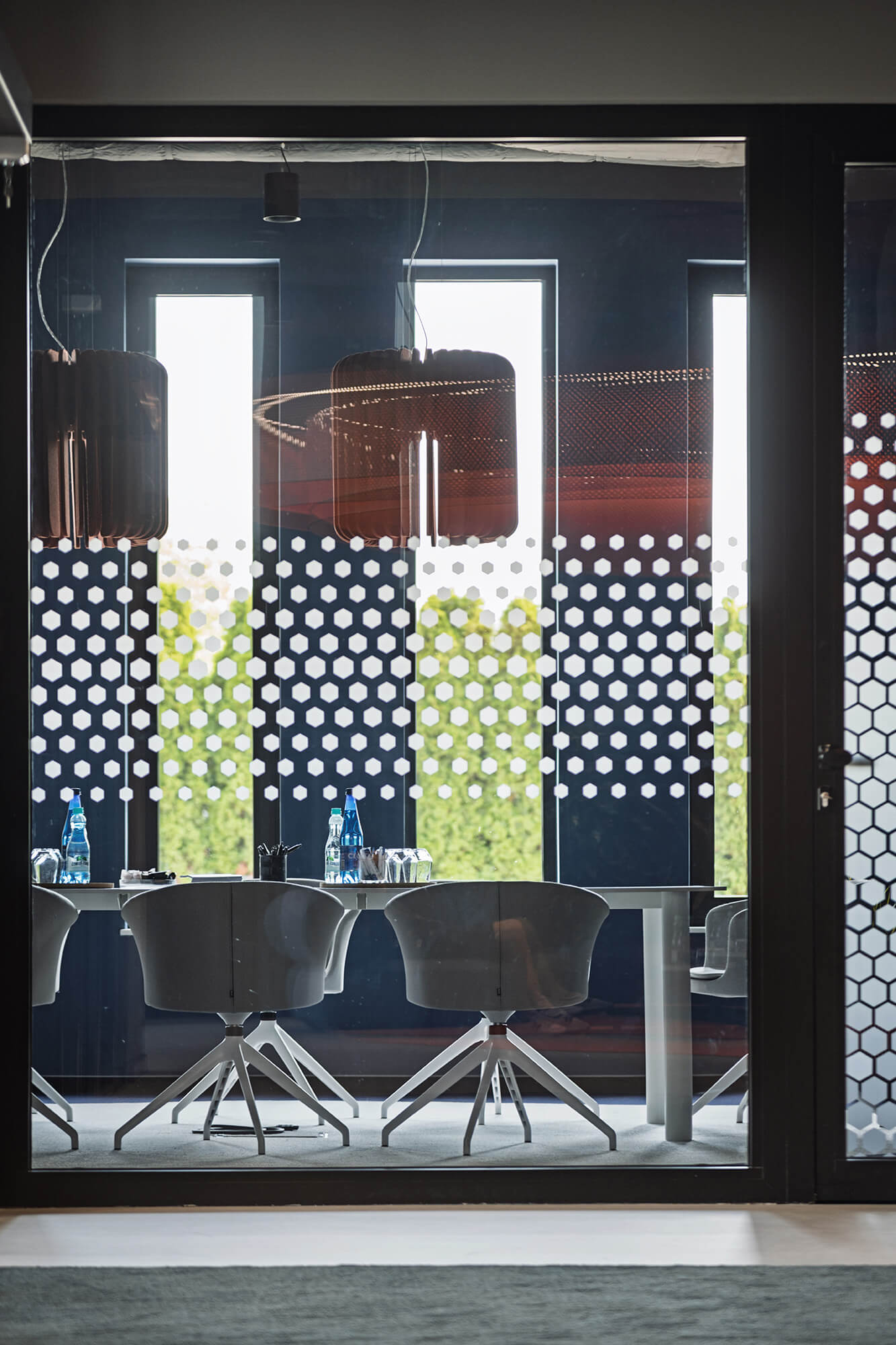 Sala konferencyjna z nowoczesnym stołem, krzesłami i dekoracyjną folią okienną.