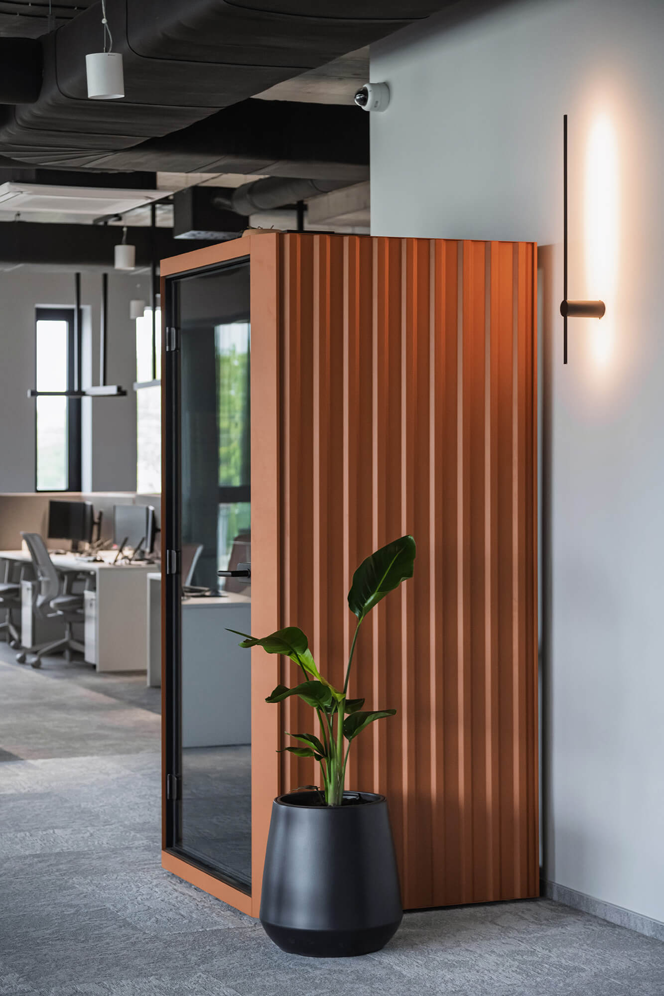 Budka akustyczna w biurze z rośliną w doniczce. Nowoczesne wnętrze biurowe.