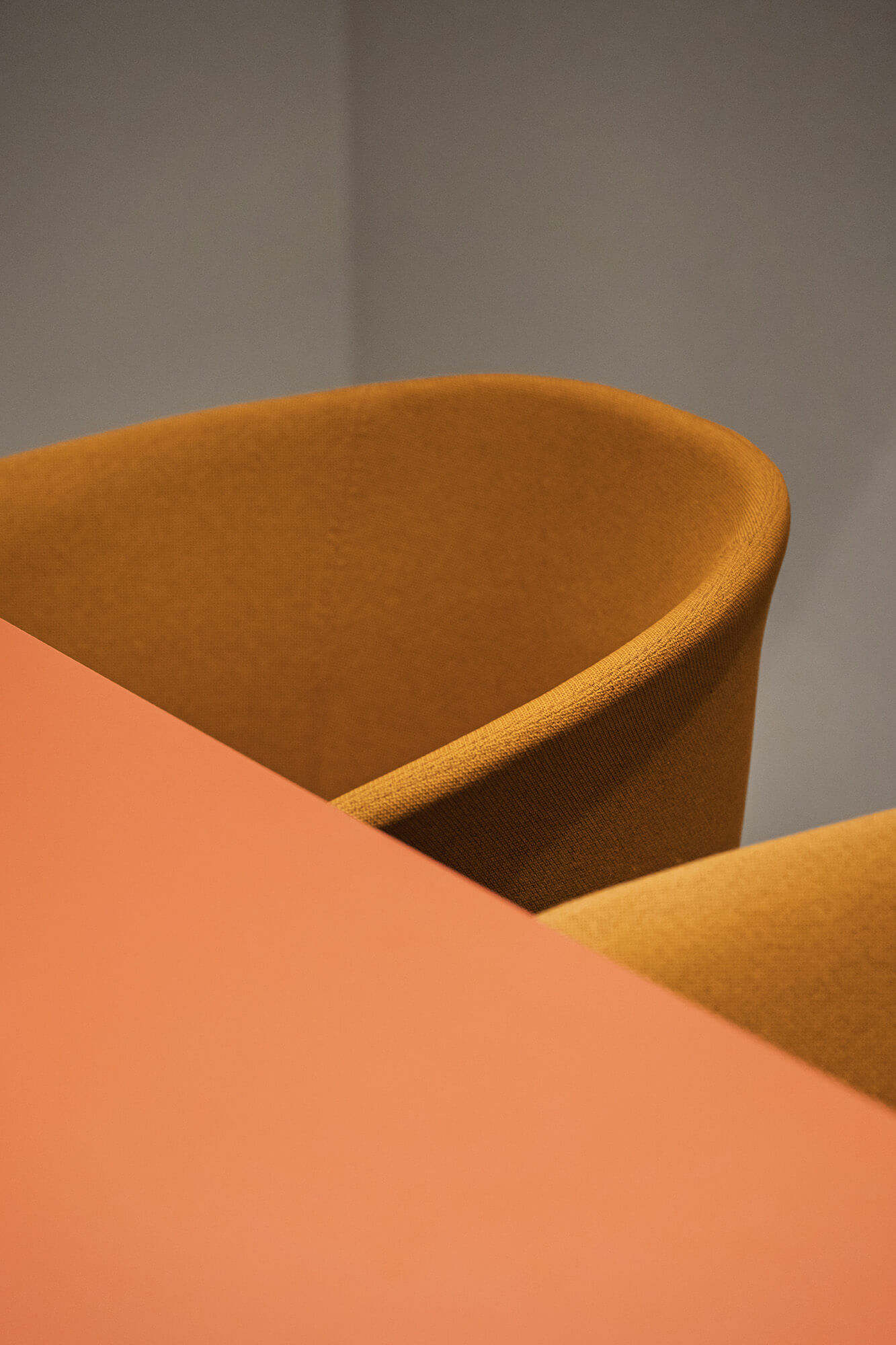 Pomarańczowy stół i żółte krzesło na tle szarej ściany. Minimalistyczny design./008k overis