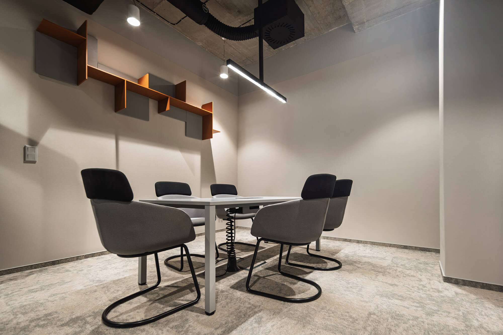 Sala konferencyjna z szarymi krzesłami i białym stołem. Nowoczesne oświetlenie i minimalistyczny design.