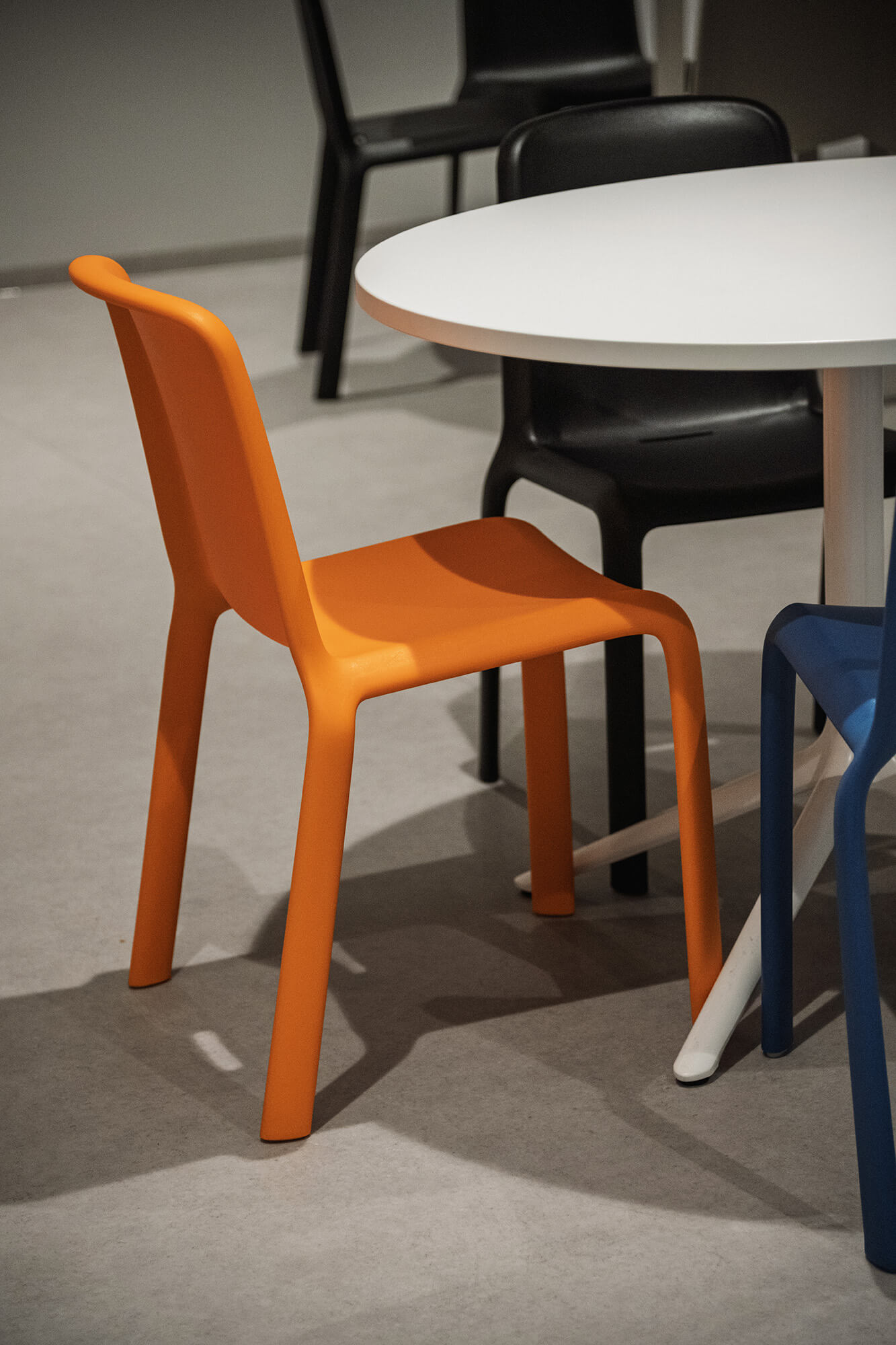 Pomarańczowe krzesło przy białym stole. Nowoczesny design, minimalistyczne wnętrze.