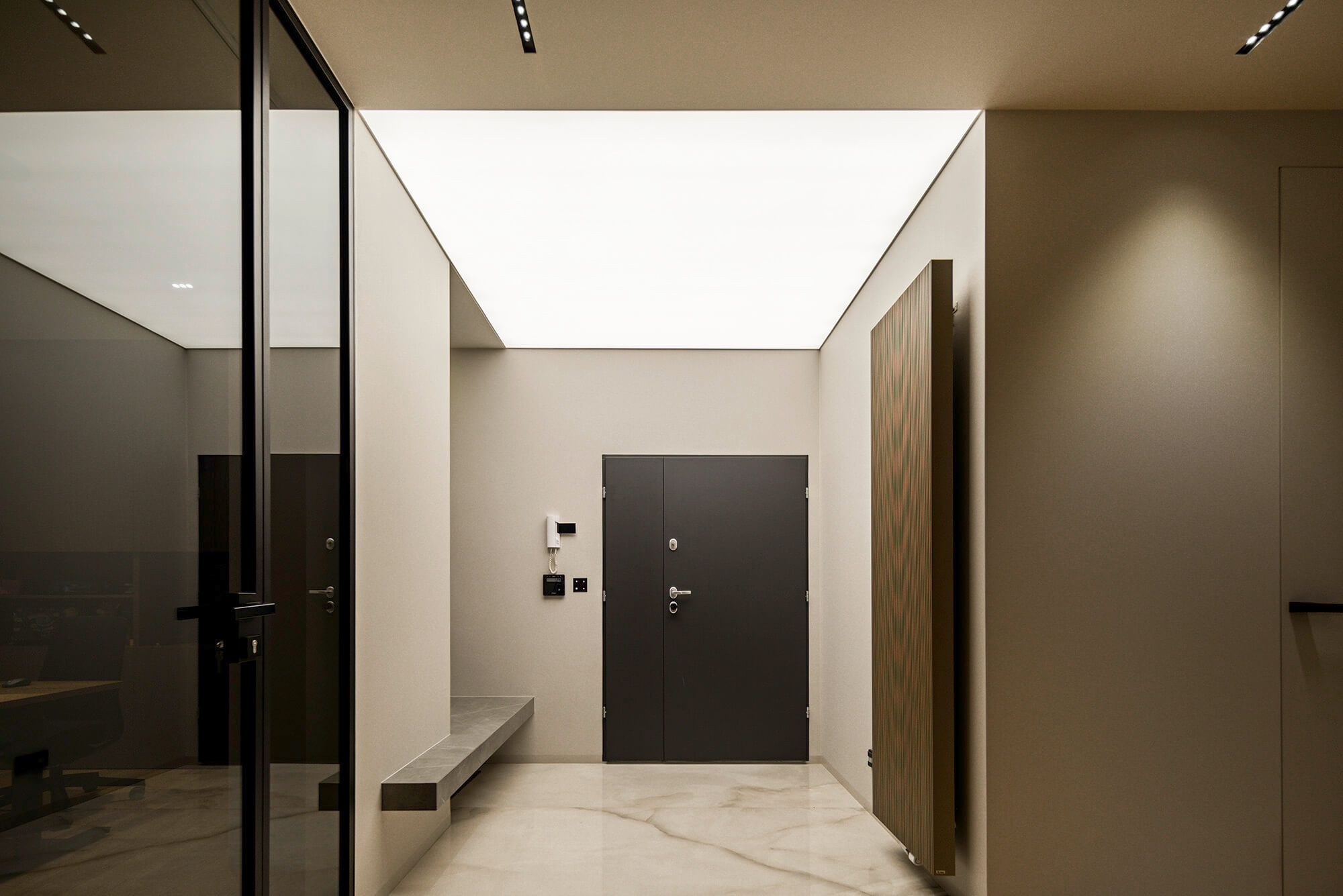 Nowoczesny przedpokój z szarymi drzwiami, marmurową podłogą i oświetleniem sufitowym.