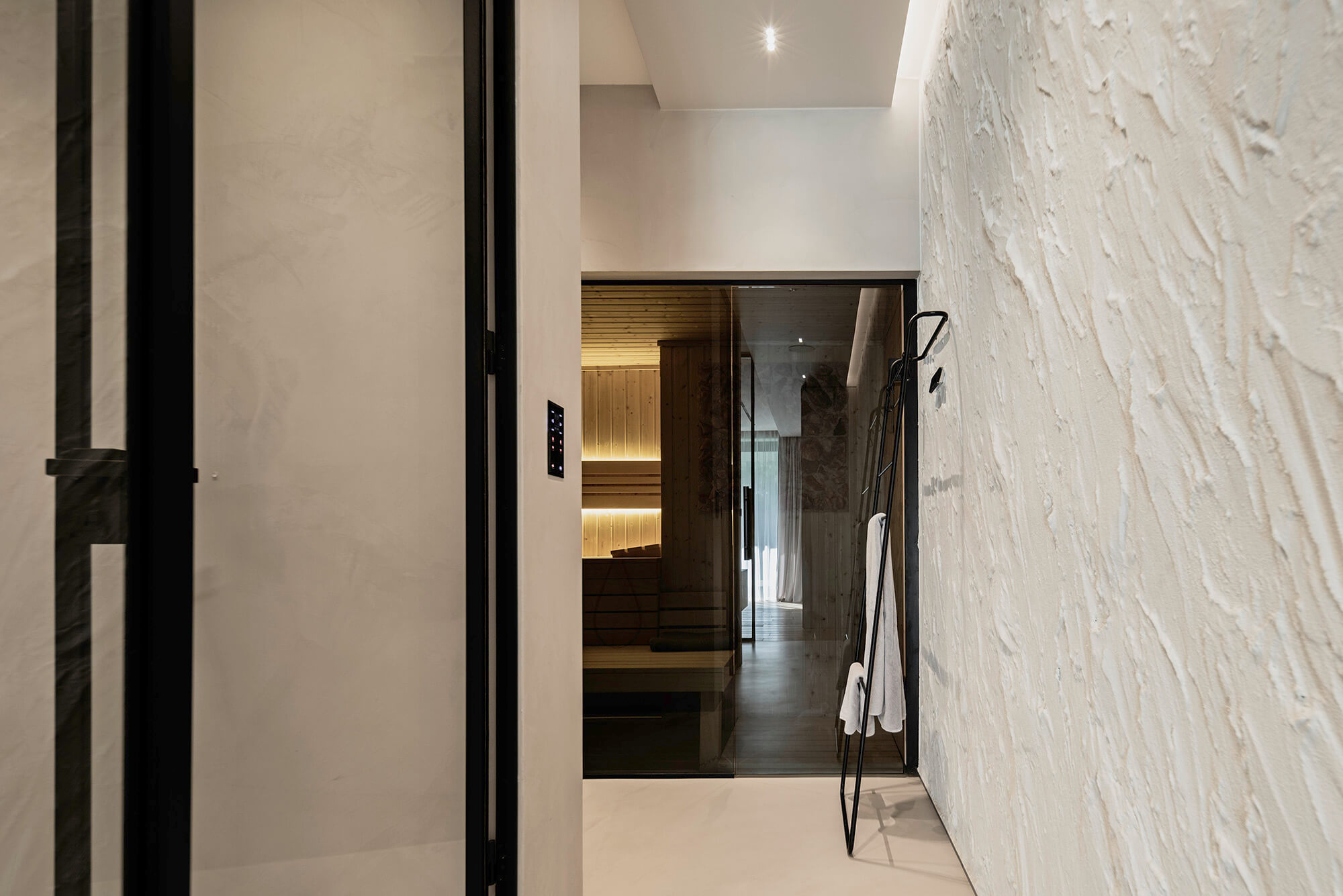 Wnętrze łazienki z sauną, widok przez otwarte drzwi. Nowoczesny design, minimalistyczny styl.