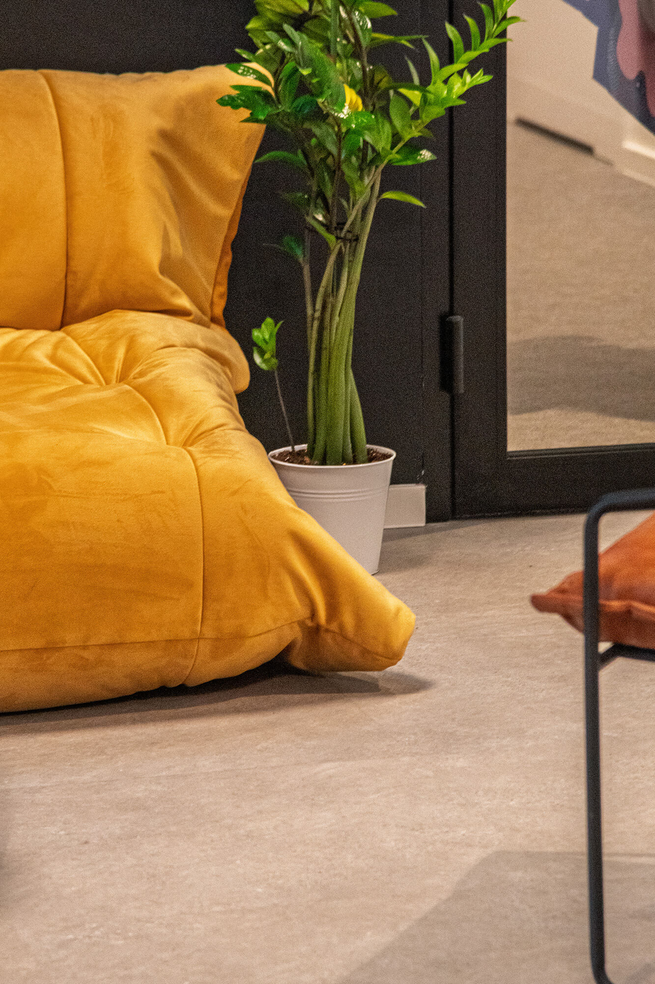 Żółta sofa obok zielonej rośliny w białej doniczce. Minimalistyczny design.