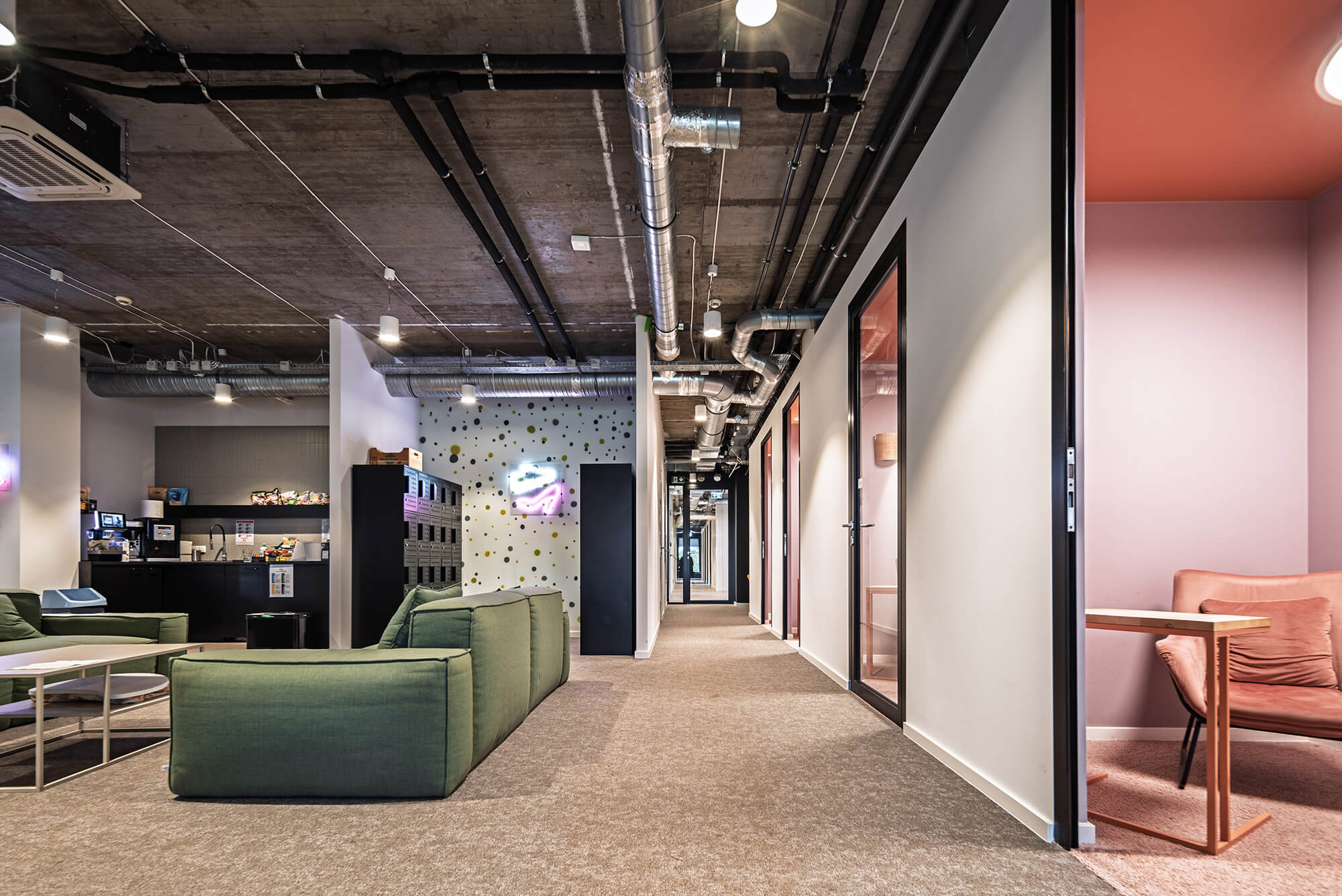 Modern office with open floor plan, collaborative seating, and exposed ductwork.