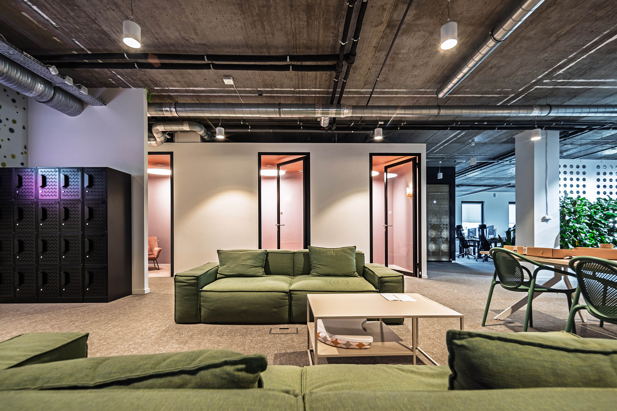 Nowoczesne biuro z zieloną sofą, stolikiem i otwartą przestrzenią.