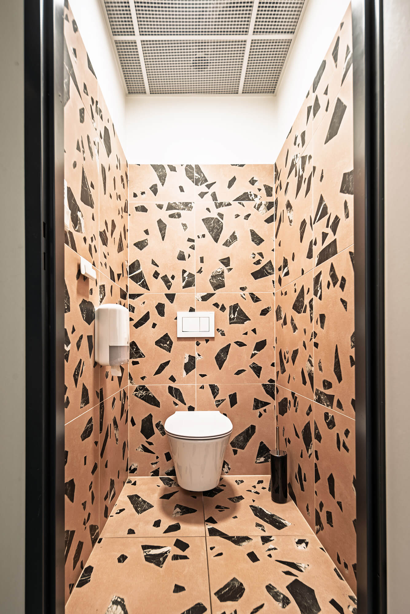Toaleta z terakotowymi płytkami w czarno-białe wzory.