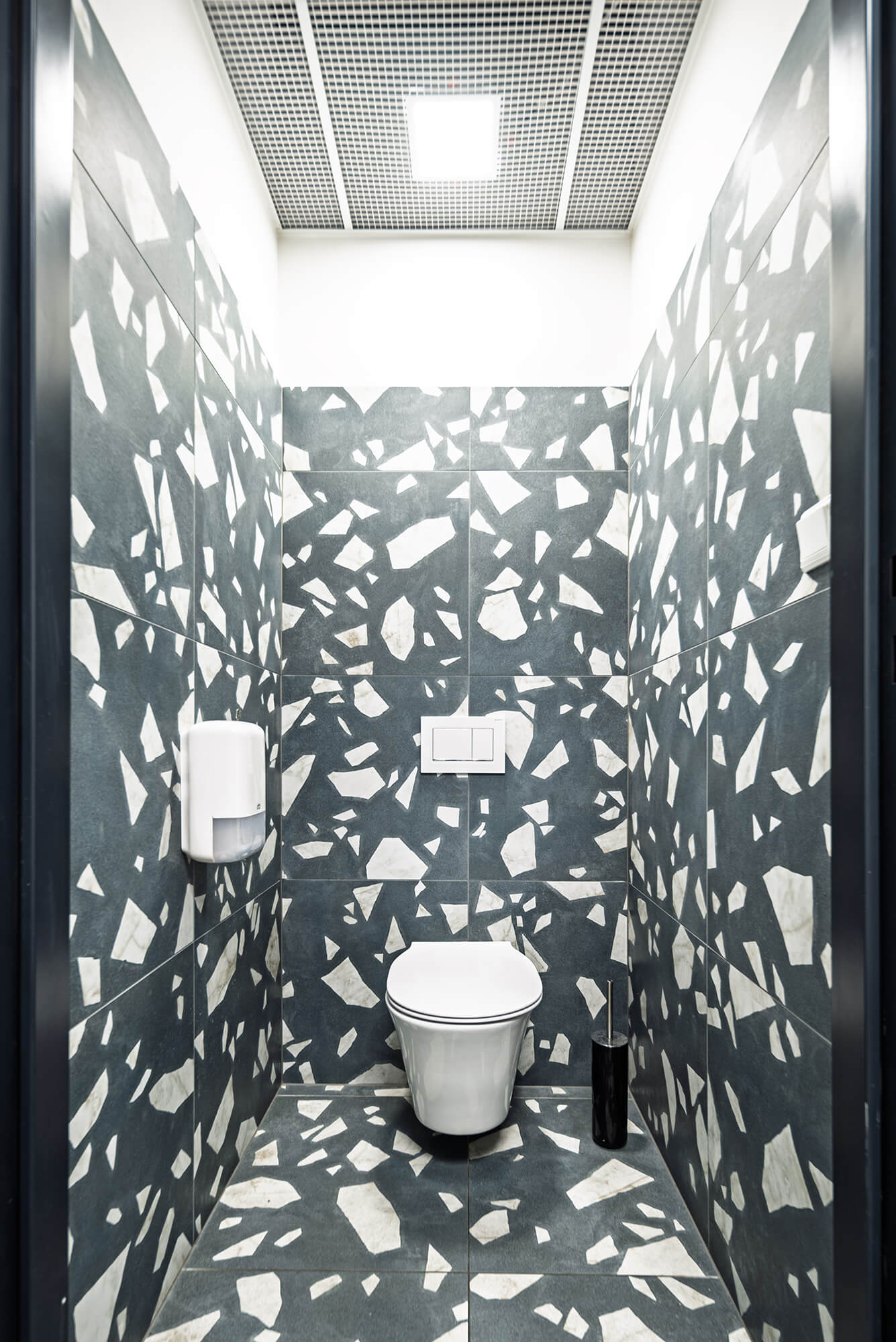 Nowoczesna kabina łazienkowa z geometrycznymi, czarno-białymi kafelkami na ścianach