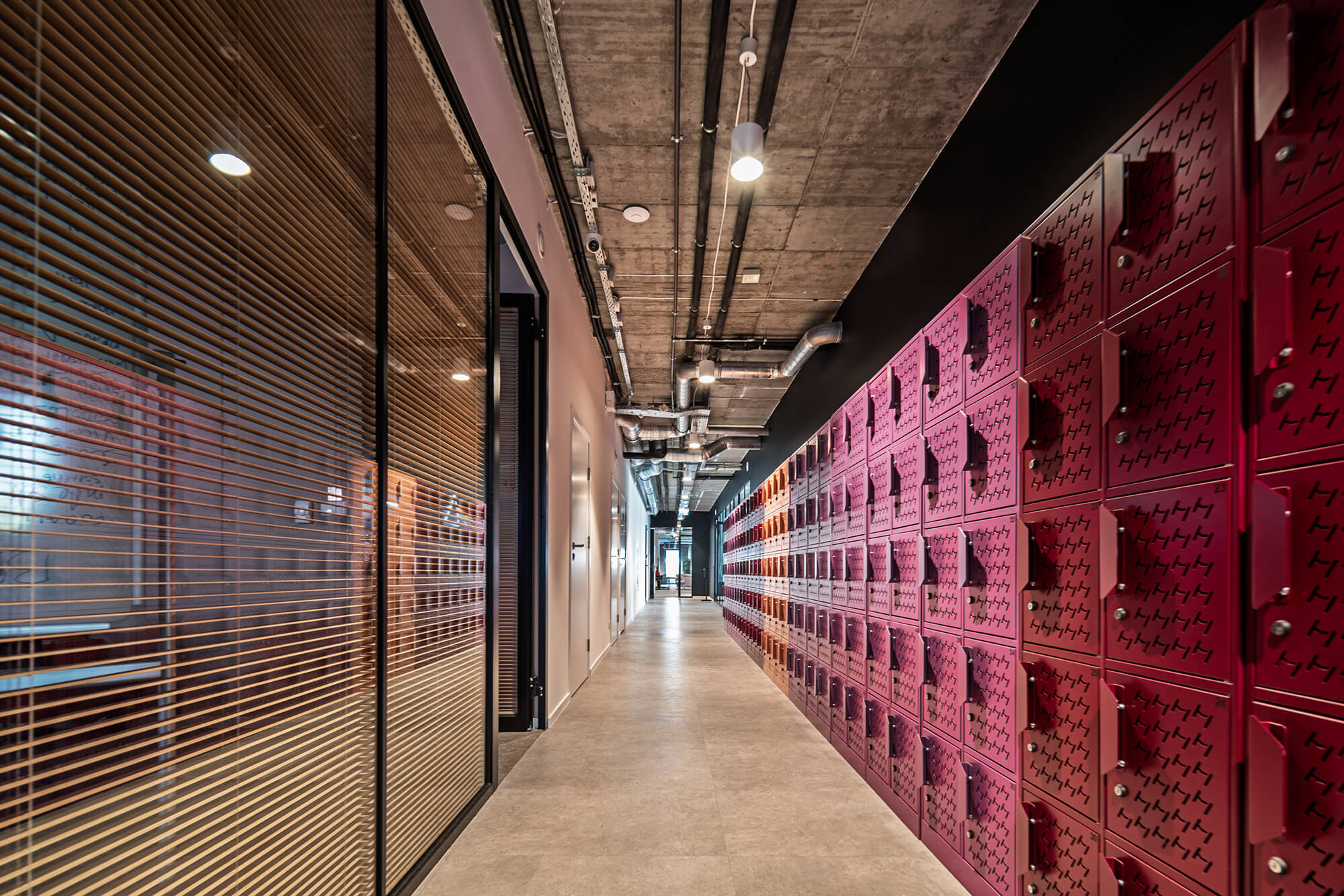 Korytarz biurowy z czerwonymi szafkami i szklanymi ścianami. Nowoczesne biuro.