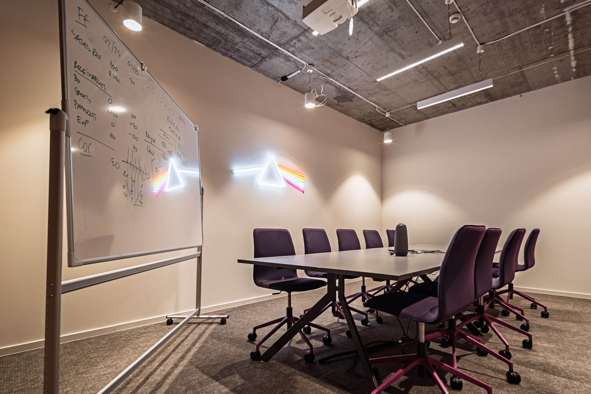 Sala konferencyjna z tablicą i neonem Pink Floyd.