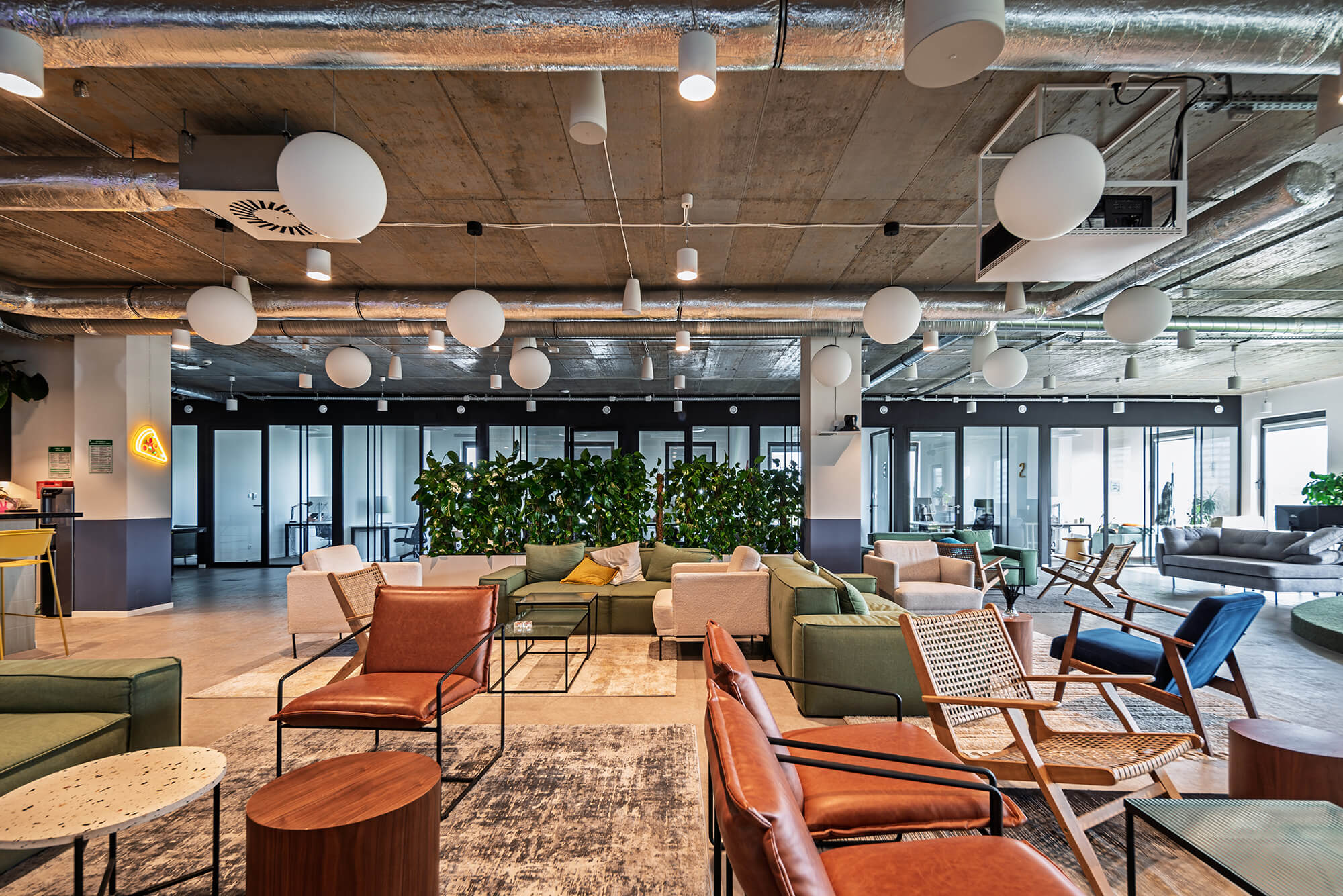 Wnętrze nowoczesnego biura z sofami, fotelami i roślinami.